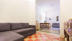 A living room with a grey sofa, a dining table with chairs, a grey sofa in the background, and a patterned rug. - Rental In Rome Arenula Apartment (Rome)
