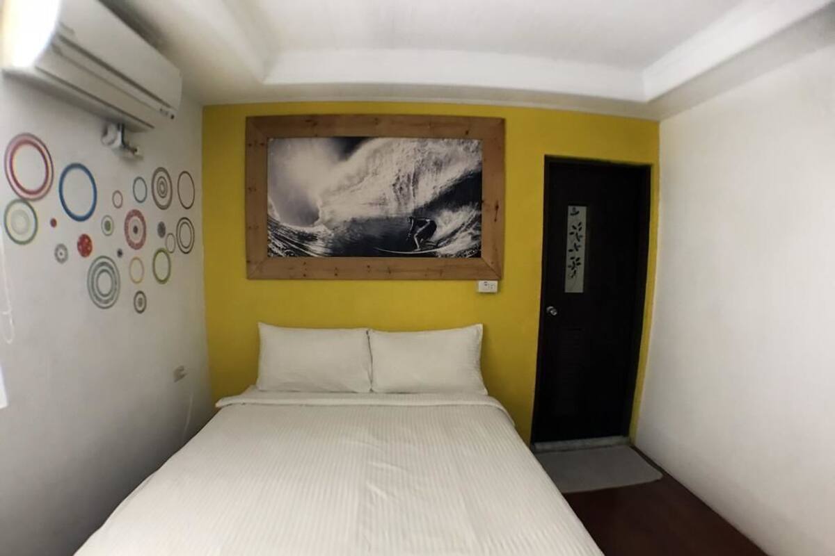 Habitació d'hotel amb un llit, un quadre a la paret i una porta.