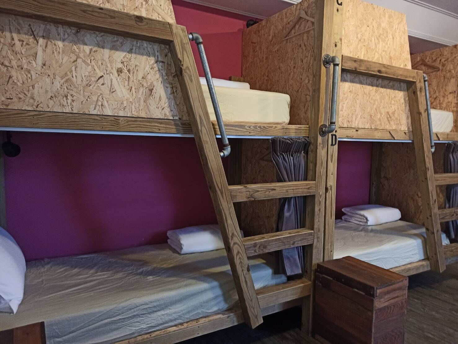 Bunk beds with wooden frames and metal ladders, a purple wall, and a small wooden chest.