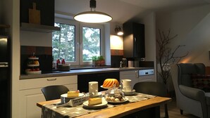 A modern kitchen with a dining area, featuring a wooden table with a cake and a sign saying "Happiness is a piece of cake". - Mountain idyll in the Steigerhaus Sauerland - DG Nord (Andreasberg)