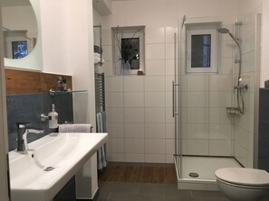 Um banheiro moderno com box de vidro, pia branca e vaso sanitário.