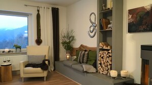 Una sala de estar con un sofá, un sillón, una chimenea y vistas al exterior.