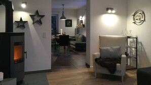 Una sala moderna con chimenea, un sofá, un comedor y un pasillo que conduce a otra habitación.