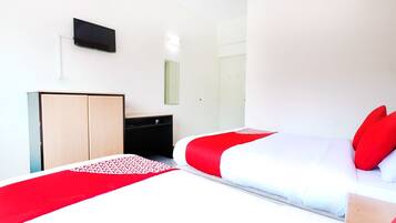 Una habitación de hotel moderna con una cama, un armario, un escritorio y un televisor montado en la pared.