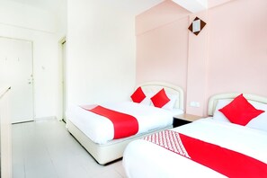 Habitación de hotel con dos camas, cada una con ropa de cama roja y blanca, y una pared de acento rosa.