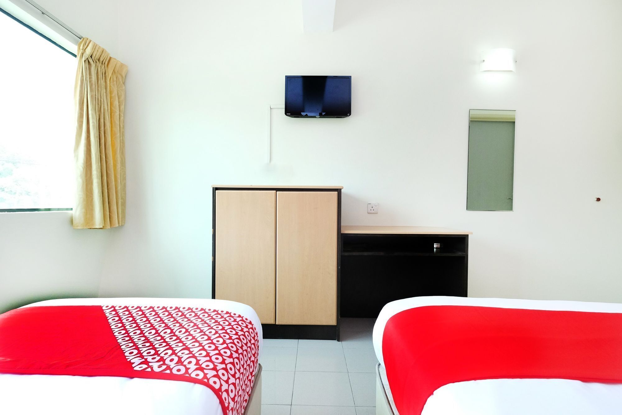 Habitación de hotel con dos camas, un armario, un escritorio, un televisor y una ventana con cortinas.