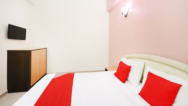 Una habitación de hotel con cama, escritorio y televisión en la pared.