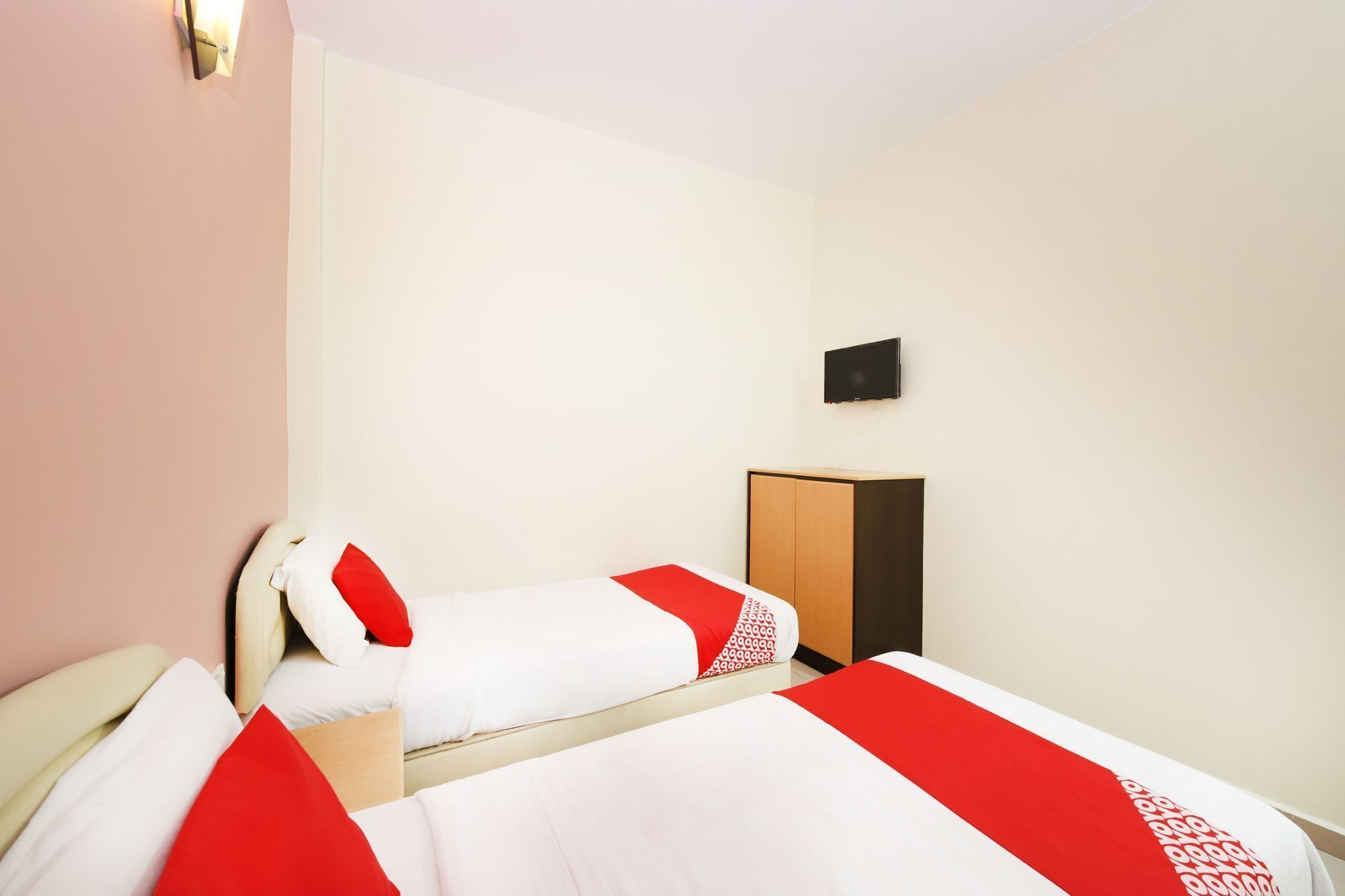 A hotel room with two beds, a wardrobe, and a flat-screen TV on the wall.
