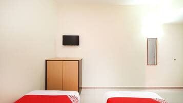 A hotel room with two beds, a television on the wall, and a mirror.