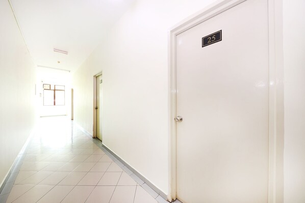 A hallway with a white door labeled "25" and a door with a window at the end.
