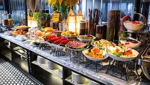 A buffet with various food items, including fruits, vegetables, and meats, arranged on a marble counter. - Acoustic Hotel & Spa (Hanoi)