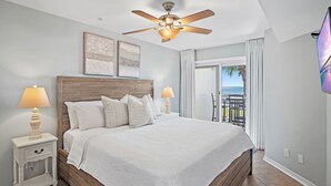 A bedroom with a large bed, two bedside lamps, a ceiling fan, and a view of the outdoors. - ***DIRECT GULF VIEWS**FREE UMBRELLA SERVICE**PET FRIENDLY**UPSCALE CONDO** (Miramar Beach)