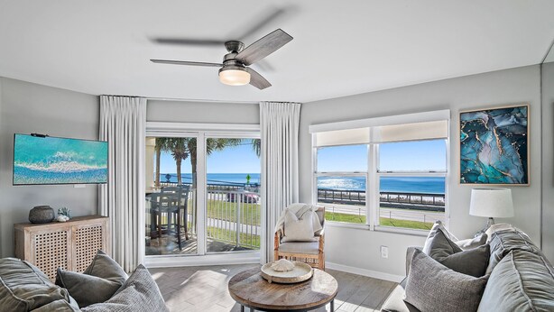 A living room with a view of the ocean, a ceiling fan, and a television on the wall. - ***DIRECT GULF VIEWS**FREE UMBRELLA SERVICE**PET FRIENDLY**UPSCALE CONDO** (Miramar Beach)