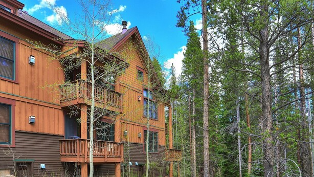 Eine große Holzhütte mit mehreren Balkonen, umgeben von einem Wald.
