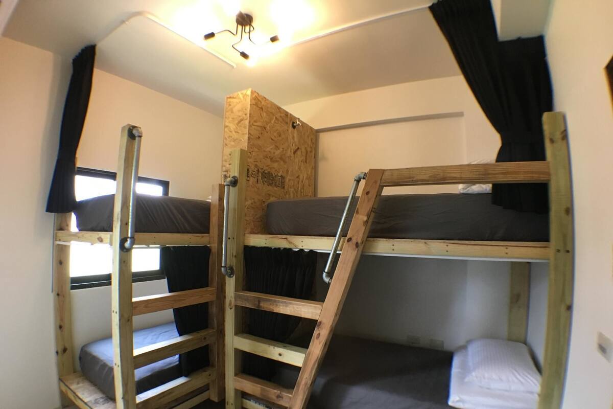 Un dormitorio con literas, una escalera y una lámpara en el techo.