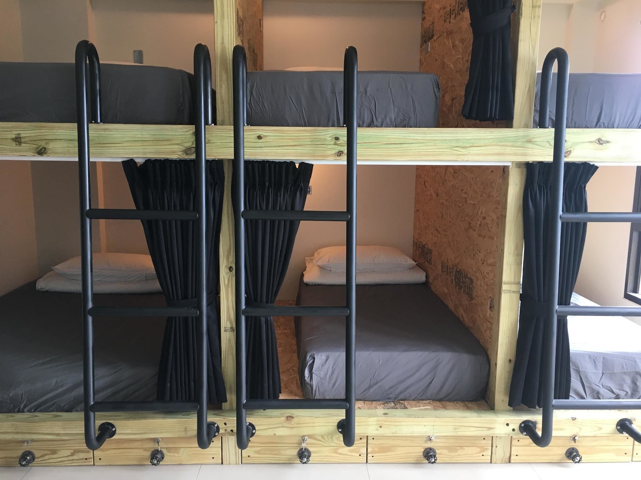 Une chambre avec un lit superposé, une structure en bois et des barreaux en métal noir.