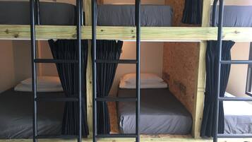 Une chambre avec un lit superposé, une structure en bois et des barreaux en métal noir.
