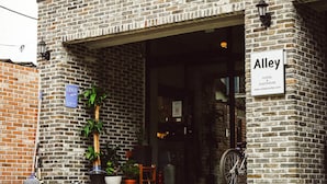 A brick building with a sign reading "Alley Hotel Guesthouse" and a website address.