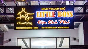 L’entrée d’un hôtel, avec une enseigne au néon indiquant : « Little Boss Home Stay ».
