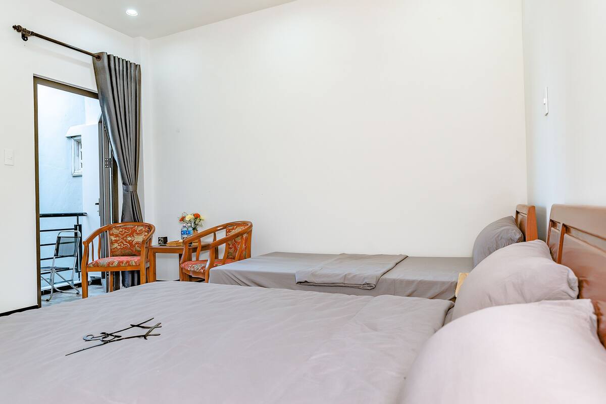 Habitación de hotel con dos camas, una silla, una mesa y vistas al exterior.