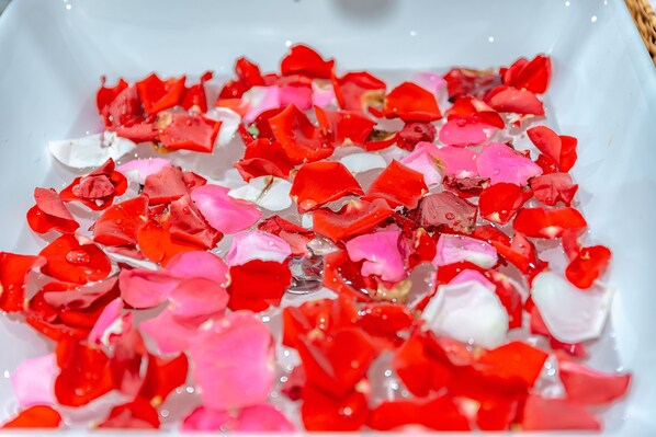 A white rectangular container filled with water and red and pink flower petals. - Little Boss Homestay (Da Nang)