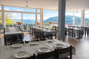 A restaurant with multiple tables set for dining, large windows offering a view of the mountains, and a modern interior design. - La Petite Pierre - ULVF Vacances (La Petite-Pierre)