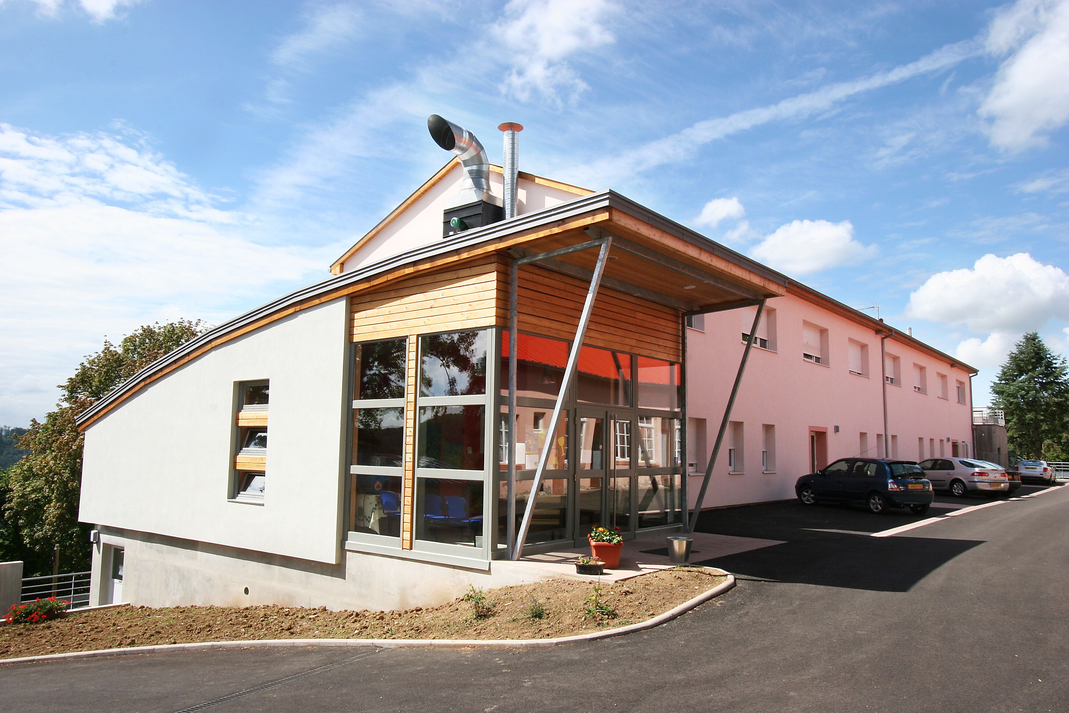 A modern building with a sloped roof, large windows, and a covered entrance.