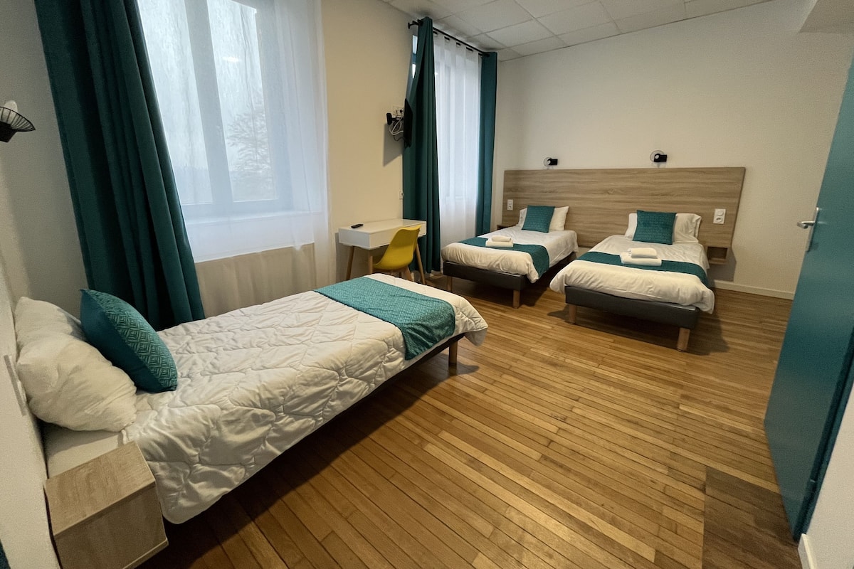 A hotel room with two single beds, a desk, and a chair.