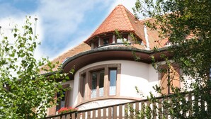 A building with a curved corner, a red-tiled roof, and a balcony with a railing. - La Petite Pierre - ULVF Vacances (La Petite-Pierre)