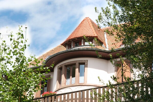 A building with a curved corner, a red-tiled roof, and a balcony with a railing. - La Petite Pierre - ULVF Vacances (La Petite-Pierre)