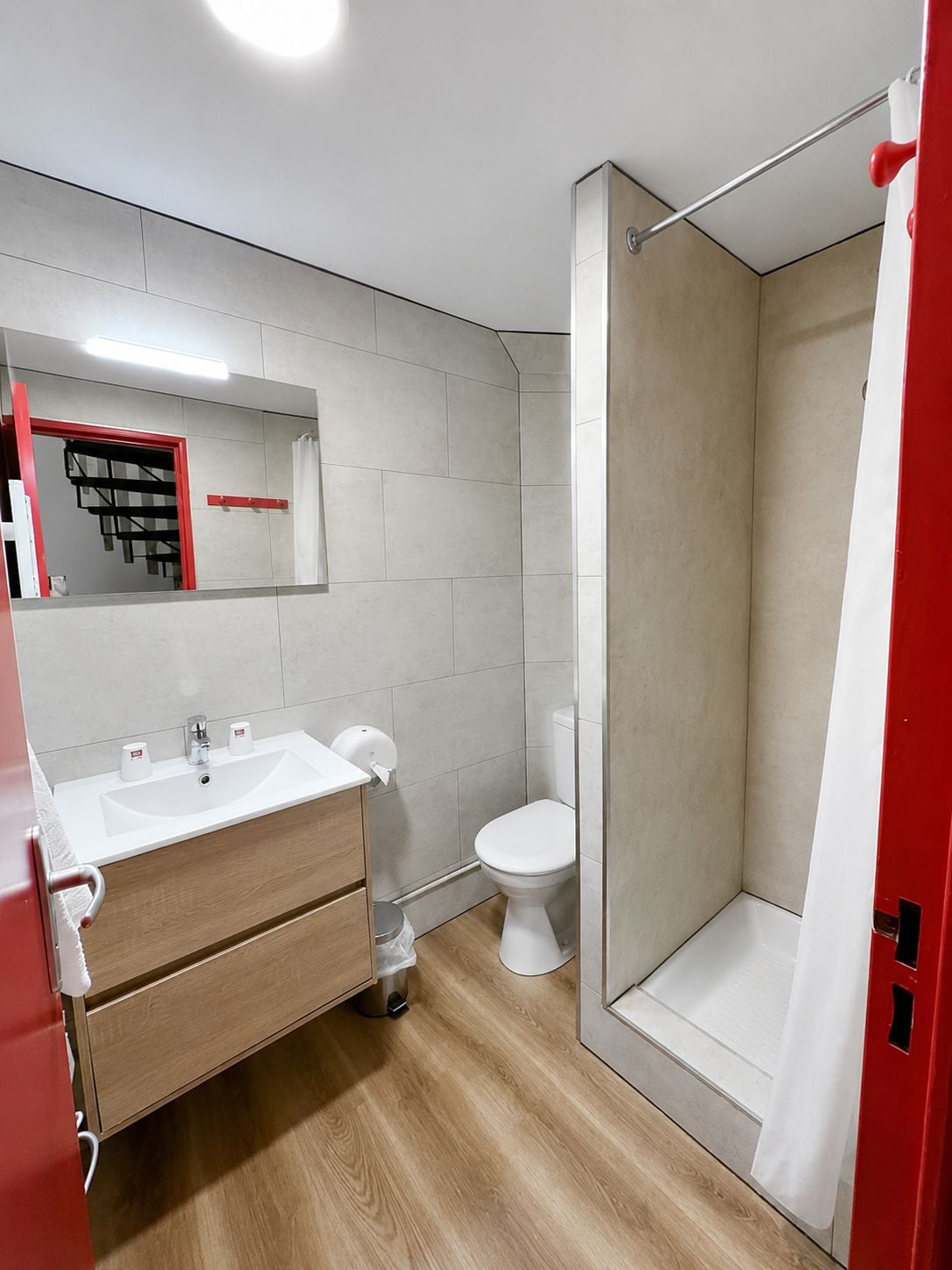 Un baño moderno con lavamanos, espejo y retrete blancos.