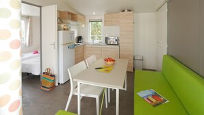 Cocina compacta con comedor, sofá verde y puerta de baño visible.