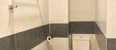 A small bathroom with a bathtub, toilet, and shower.