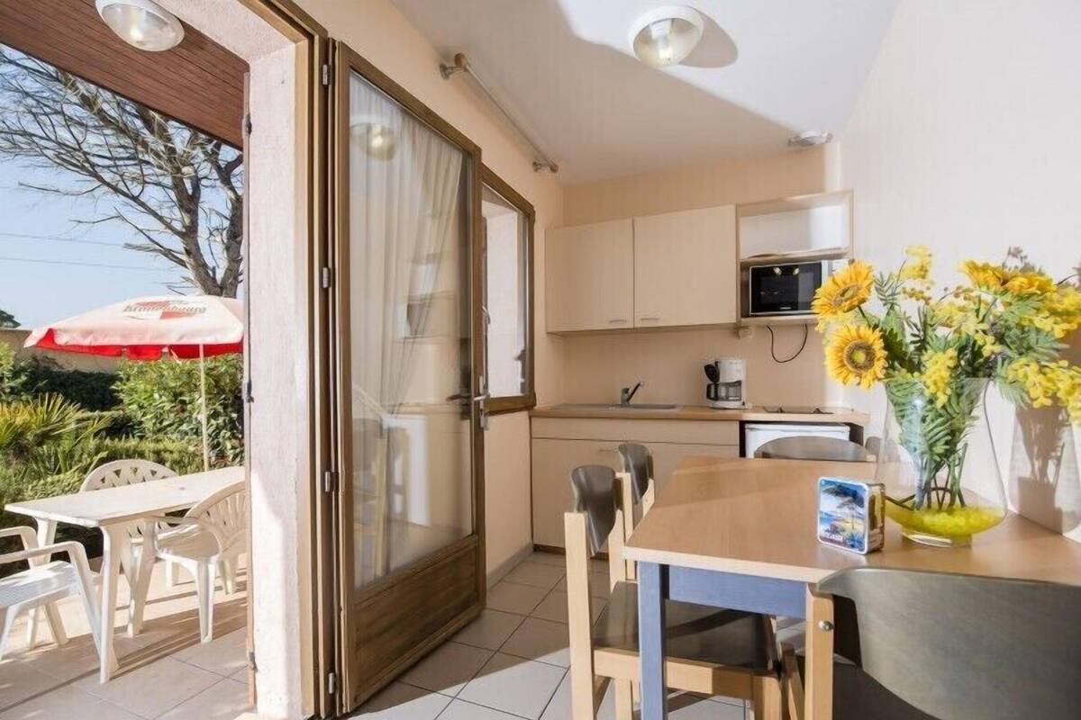 A compact kitchen with a microwave, sink, and a dining area with a table and chairs.
