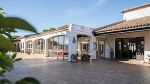 A building with a tiled patio, large glass doors, and a sign indicating it is a residence for Colombians. - Les Residences du Colombier - ULVF (Fréjus)