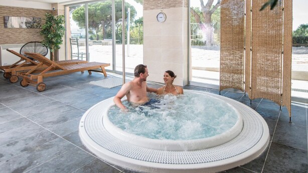 A hot tub in a well-lit indoor area with a view of the outdoors. - Les Residences du Colombier - ULVF (Fréjus)