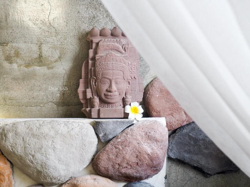 Una escultura de piedra de un rostro con una flor al frente.