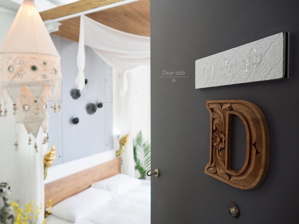 Ein Schlafzimmer mit einem Bett, einem Wandbehang und einem an der Wand befestigten Holzbuchstaben D.