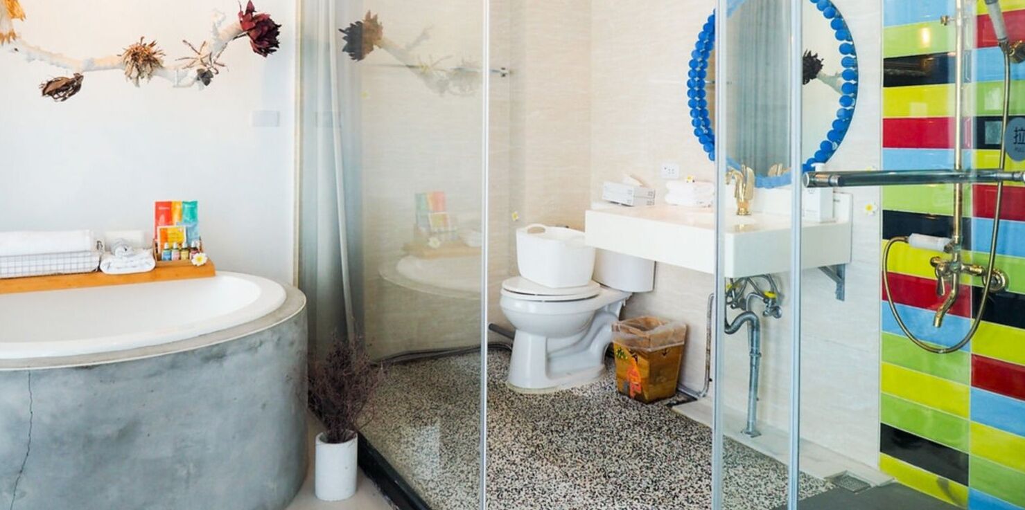 A bathroom with a marble sink, a toilet, and a shower area with a colorful tiled wall.