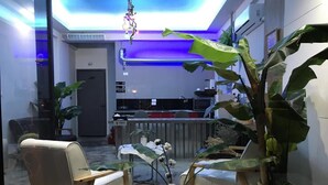 A modern interior with a reception desk, seating area, and potted plants. - Fas Glass House B&B (Xincheng)