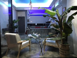 Relax in a cozy seating area surrounded by lush greenery, with a kitchen nearby.