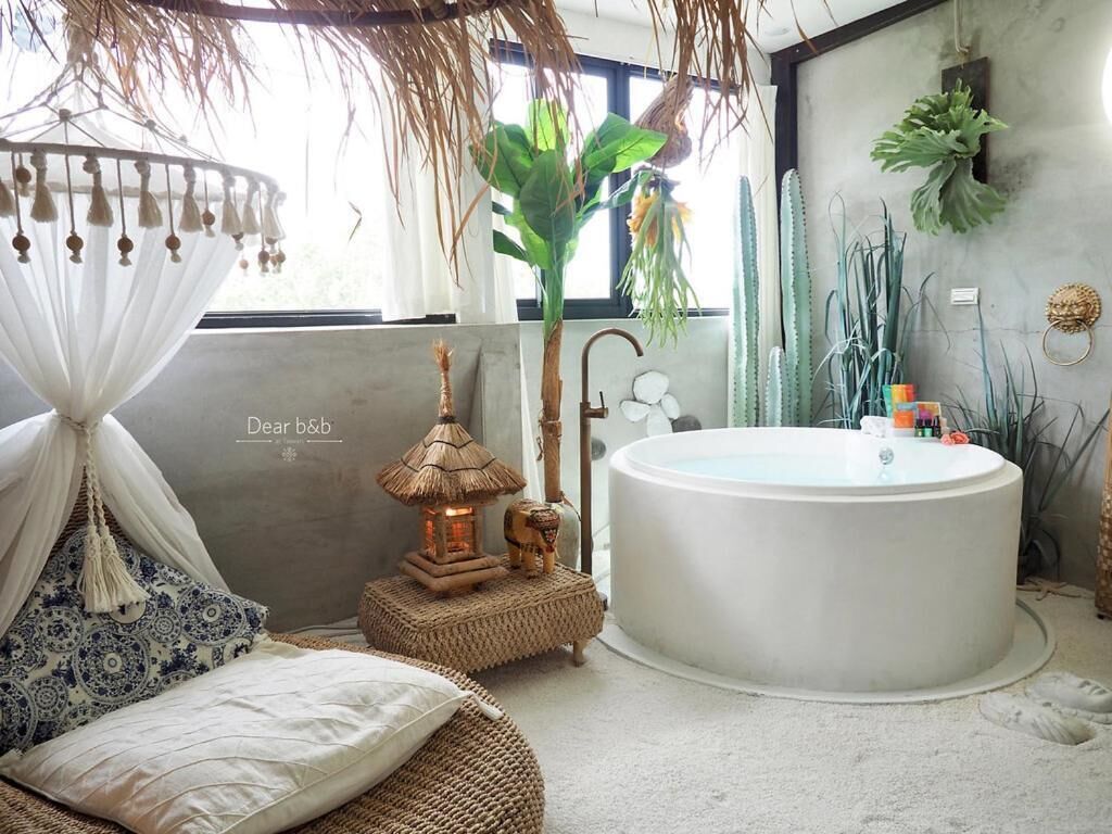 A modern bathroom with a large bathtub, a hanging chair, and a small table with a lantern.