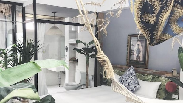 A modern bedroom with a bed, a hanging chair, and a large window. - Fas Glass House B&B (Xincheng)