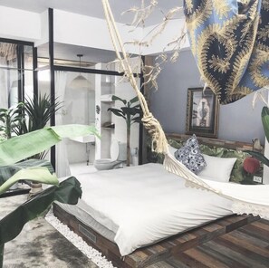 A modern bedroom with a bed, a hanging chair, and a large window. - Fas Glass House B&B (Xincheng)