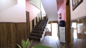 A staircase leading to a landing with a water dispenser and a refrigerator. - Greno House (Greater Noida)