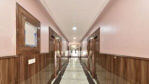 A hallway with wooden paneling, marble flooring, and a mirrored wall. - Greno House (Greater Noida)