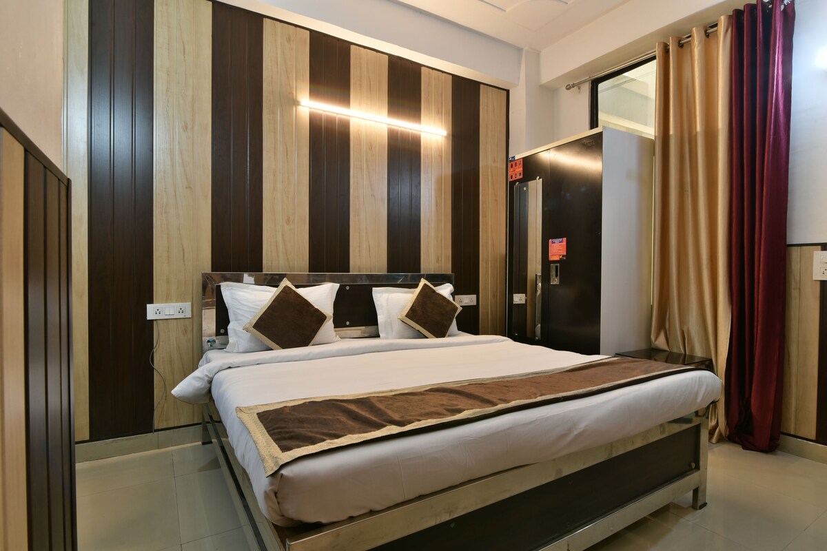 A modern hotel room with a large bed, wooden panel wall, and a sliding door closet.