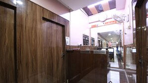 A reception area with a wooden reception desk, a sign reading "RECEPTION," and a "WELCOME" sign. - Greno House (Greater Noida)