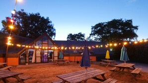 An outdoor patio area with picnic tables, umbrellas, and string lights. - Ty an Diaoul - Vacances ULVF (Sarzeau)