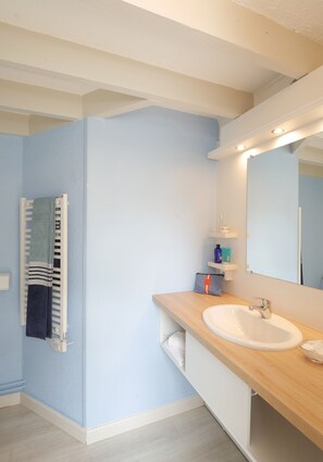 Een badkamer met een witte wastafel, een spiegel en een handdoekrek.